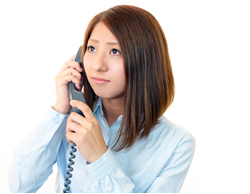 急用な電話を受けたものの、担当者が外出中で受け継ぎができなく、困っている女性社員のイメージ