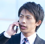 外出先から携帯電話で社内へ電話連絡をする営業マンのイメージ