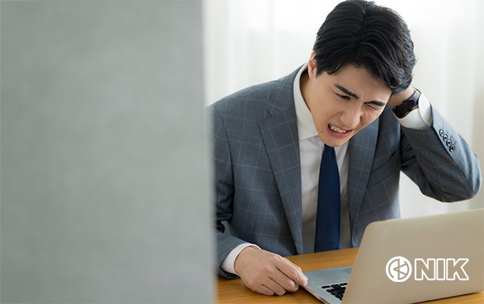 PCの前で頭を抱える「なんでも担当者」さん。イメージ